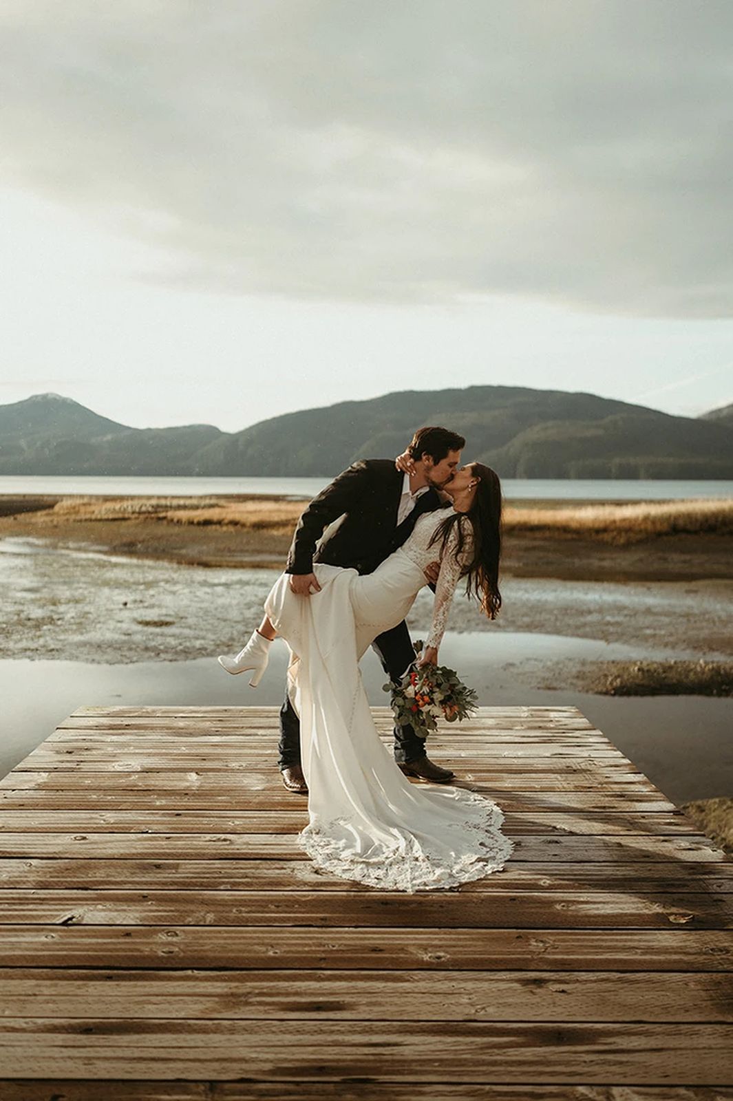 Alaska Wedding Photographer captures a Cordova couple kissing with dramatic mountains as their backdrop.