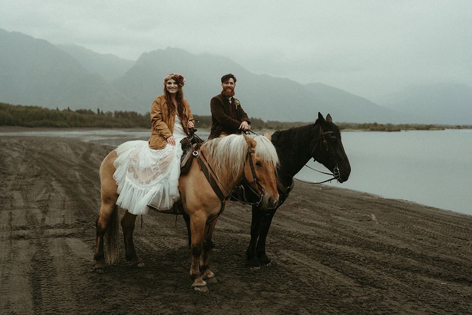 During their Alaska elopement, a couple exchanges vows on horseback with a dramatic mountain backdrop.