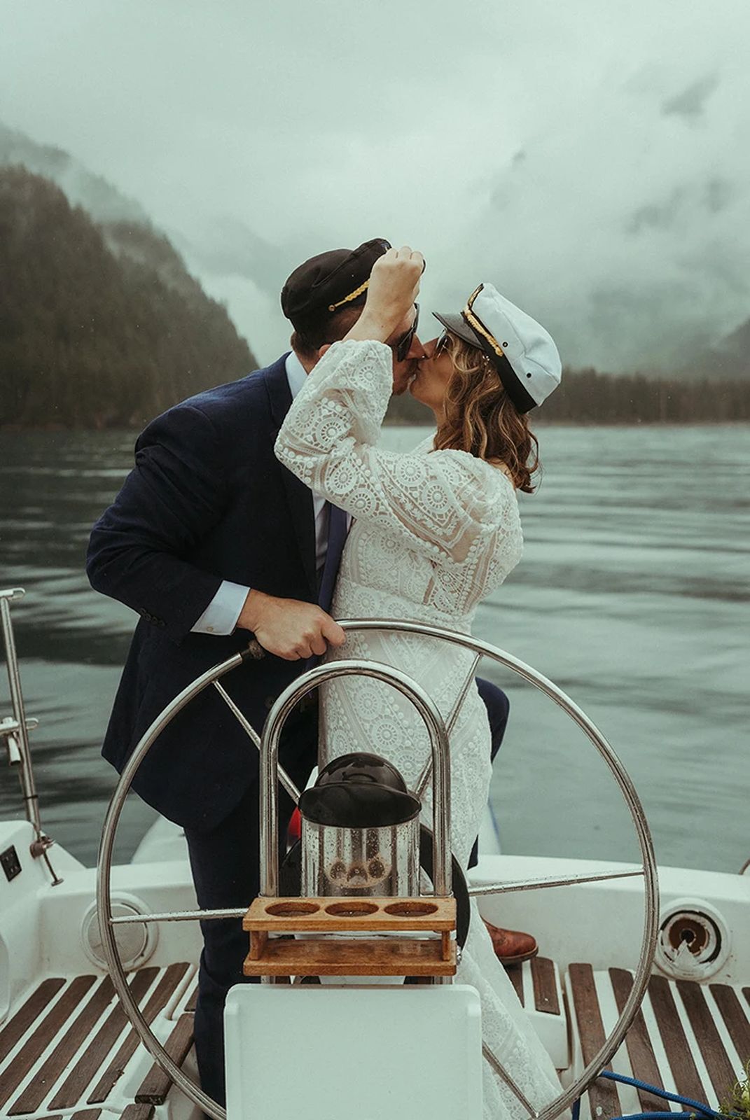 During their Seward, Alaska sailboat elopement, a couple embraces in a kiss with a dramatic mountain backdrop.